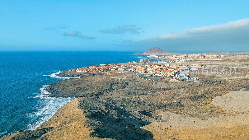 Aerial view of the coast in the natural reserve of "Montaña Pelada" and town of El Medano in the background. Tenerife, Canary Islands. Drone shot